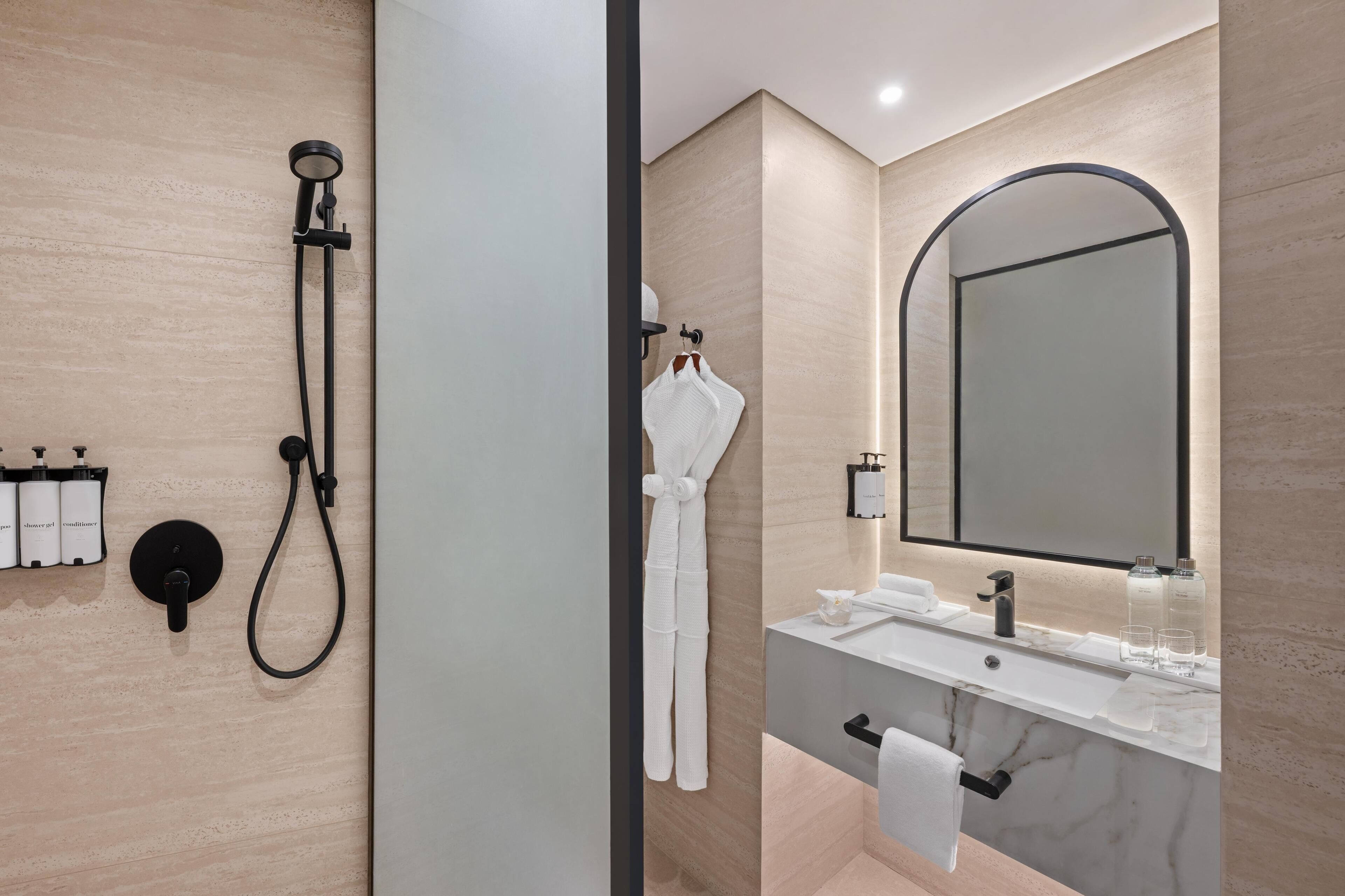 Een moderne badkamer met een douche, een wastafel en een grote spiegel.