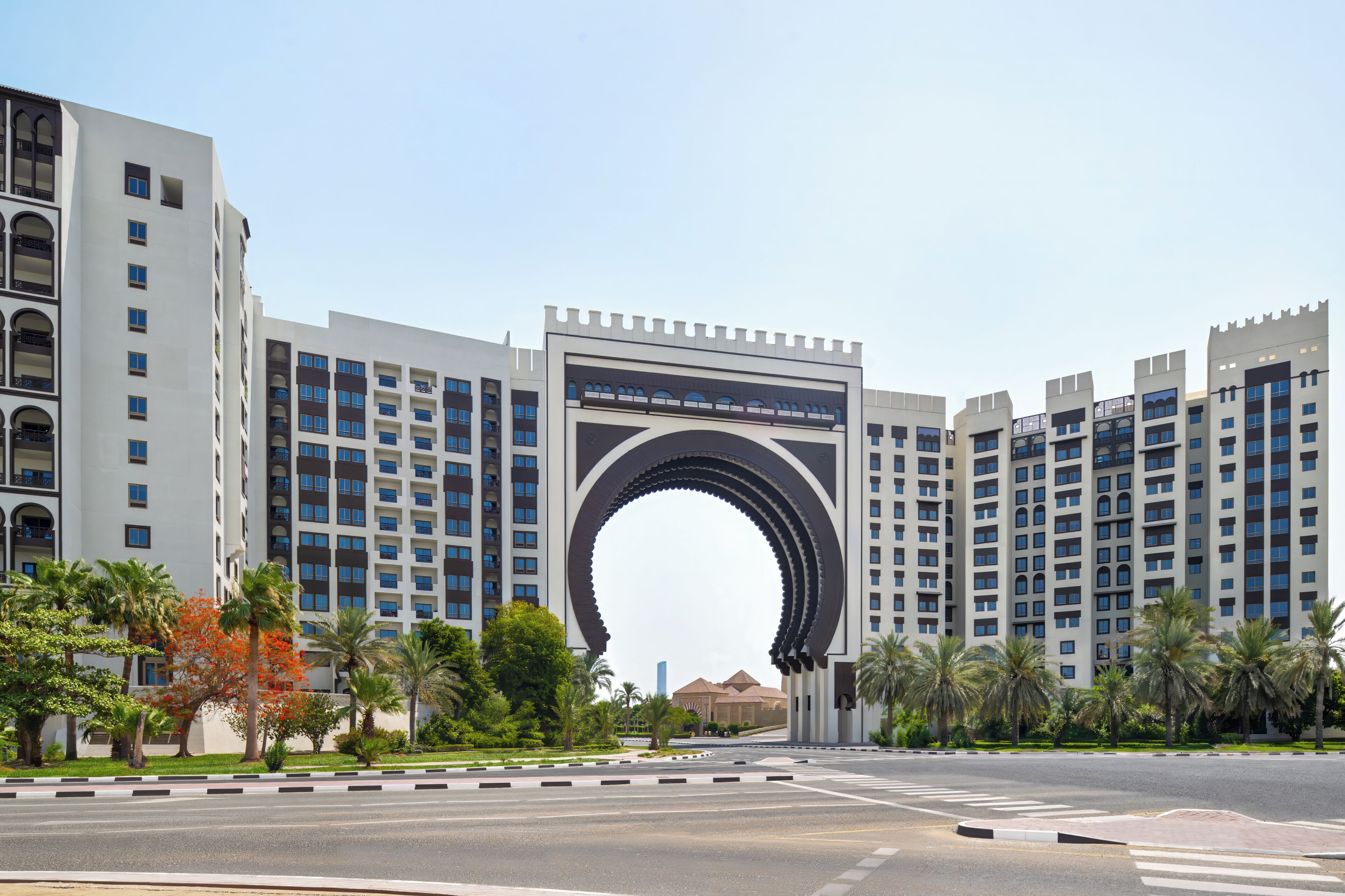 A modern building with a large archway entrance, multiple floors, and a clear sky.