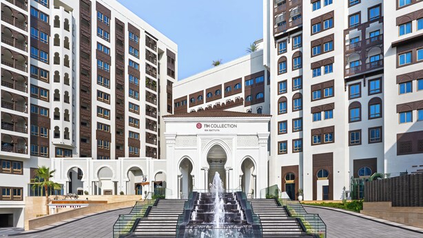 A hotel entrance with a central fountain, multiple balconies, and a clear sky. - NH Collection Dubai Ibn Battuta (Dubai)