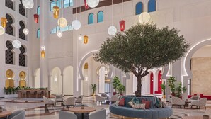 A spacious lobby with a central seating area, multiple tables, and hanging spherical light fixtures.