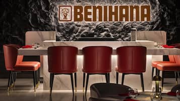 Een restaurant met een marmeren toonbank, rode stoelen en een logo aan de muur.