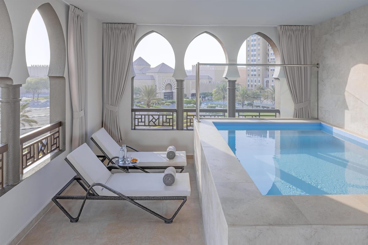 Ein Balkon mit Pool, Liegestühlen und einem Tisch mit Handtuch und Gläsern.