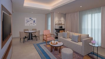 A modern hotel room with a flat-screen TV, a dining area with a round table and chairs, a sofa with cushions, and a coffee table with a tray.