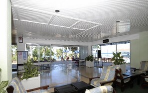 A spacious indoor area with a high ceiling, large windows, and a view of the beach. There are several chairs and tables arranged for seating. - Mombasa Beach Hotel (Mombasa)