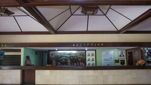 Un mostrador de recepción con un mural, un reloj y un cuadro enmarcado.