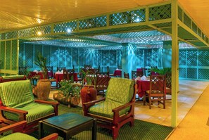 A covered outdoor seating area with wooden chairs and tables, surrounded by lattice panels. - Mombasa Beach Hotel (Mombasa)