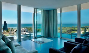 A modern living room with a large balcony, white furniture, and a view of the ocean. - The Oitavos Hotel (Cascais)