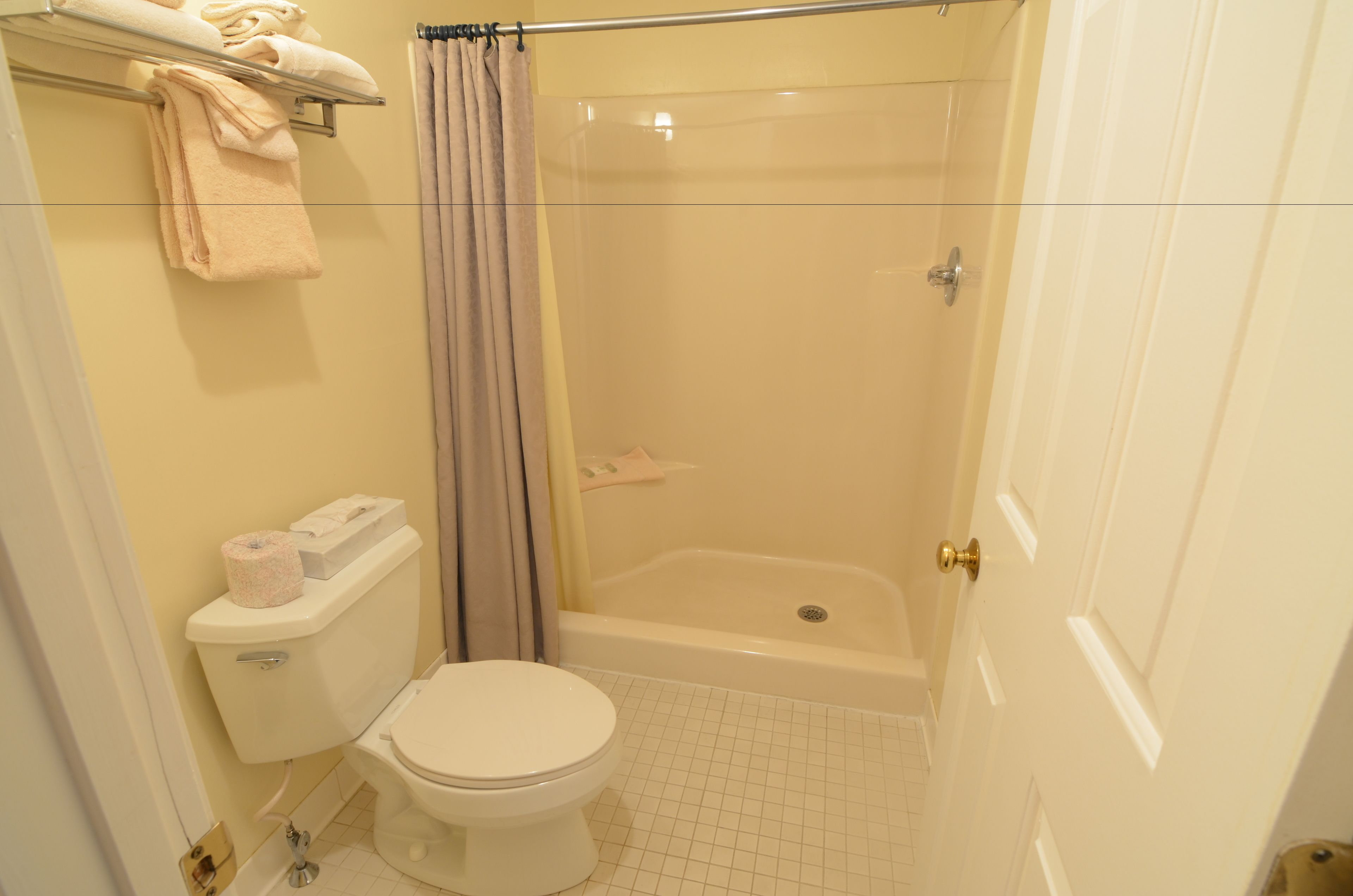 Un baño con inodoro, ducha con puerta de vidrio y bañera.