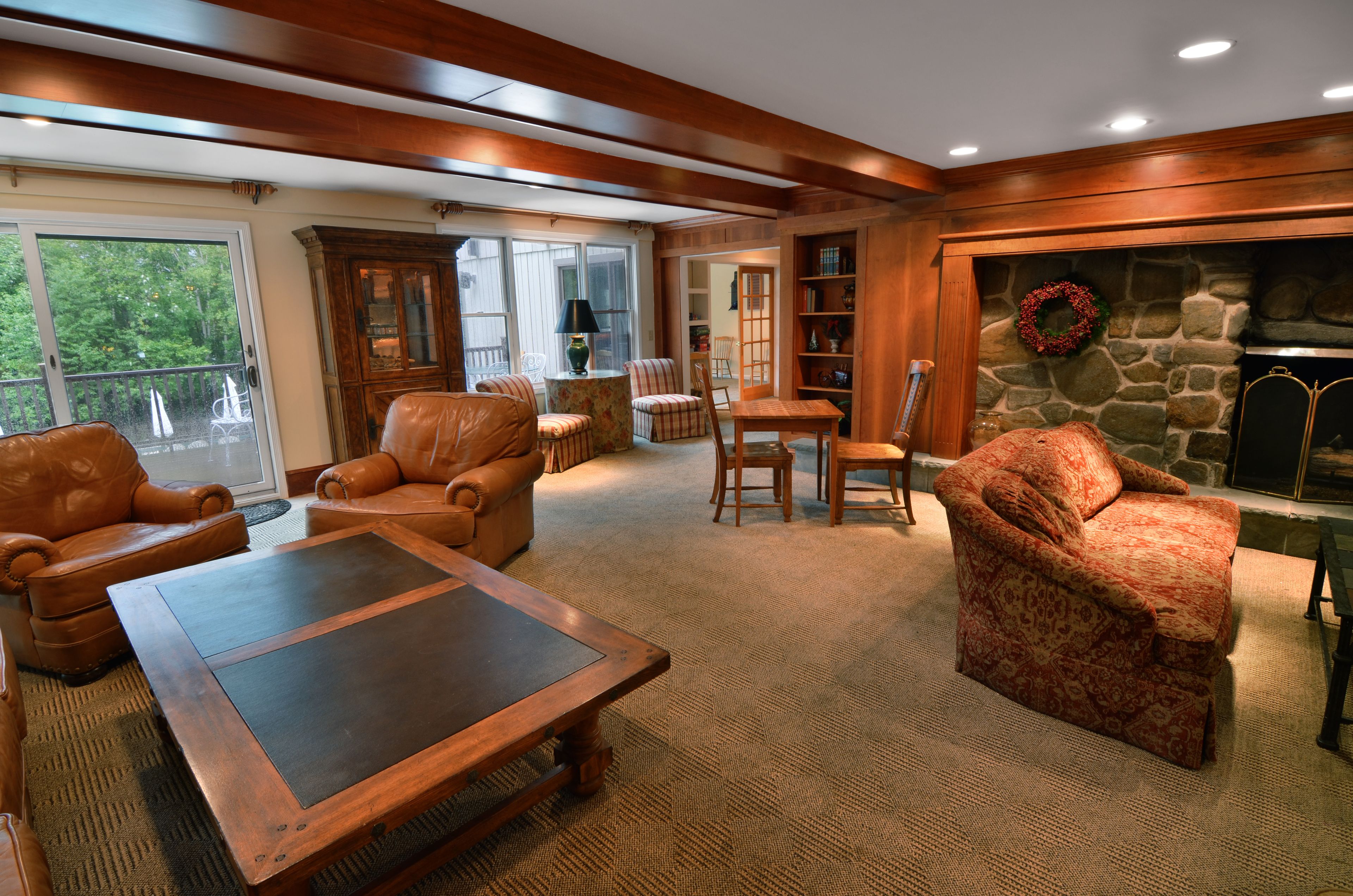 A cozy living room with leather sofas, a wooden coffee table, and a stone fireplace.