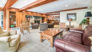 A spacious living room with a fireplace, leather sofas, wooden coffee table, and a stone fireplace surround. - The Valley Inn, an Ascend Collection Hotel (Waterville Valley)