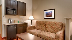 A compact hotel room with a kitchenette, a sofa, a coffee maker, and a lamp. - Holiday Inn Express & Suites Orem-North Provo by IHG (Orem)