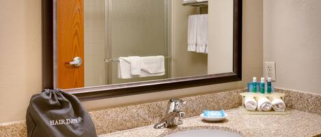 A bathroom with a sink, mirror, and toiletries.