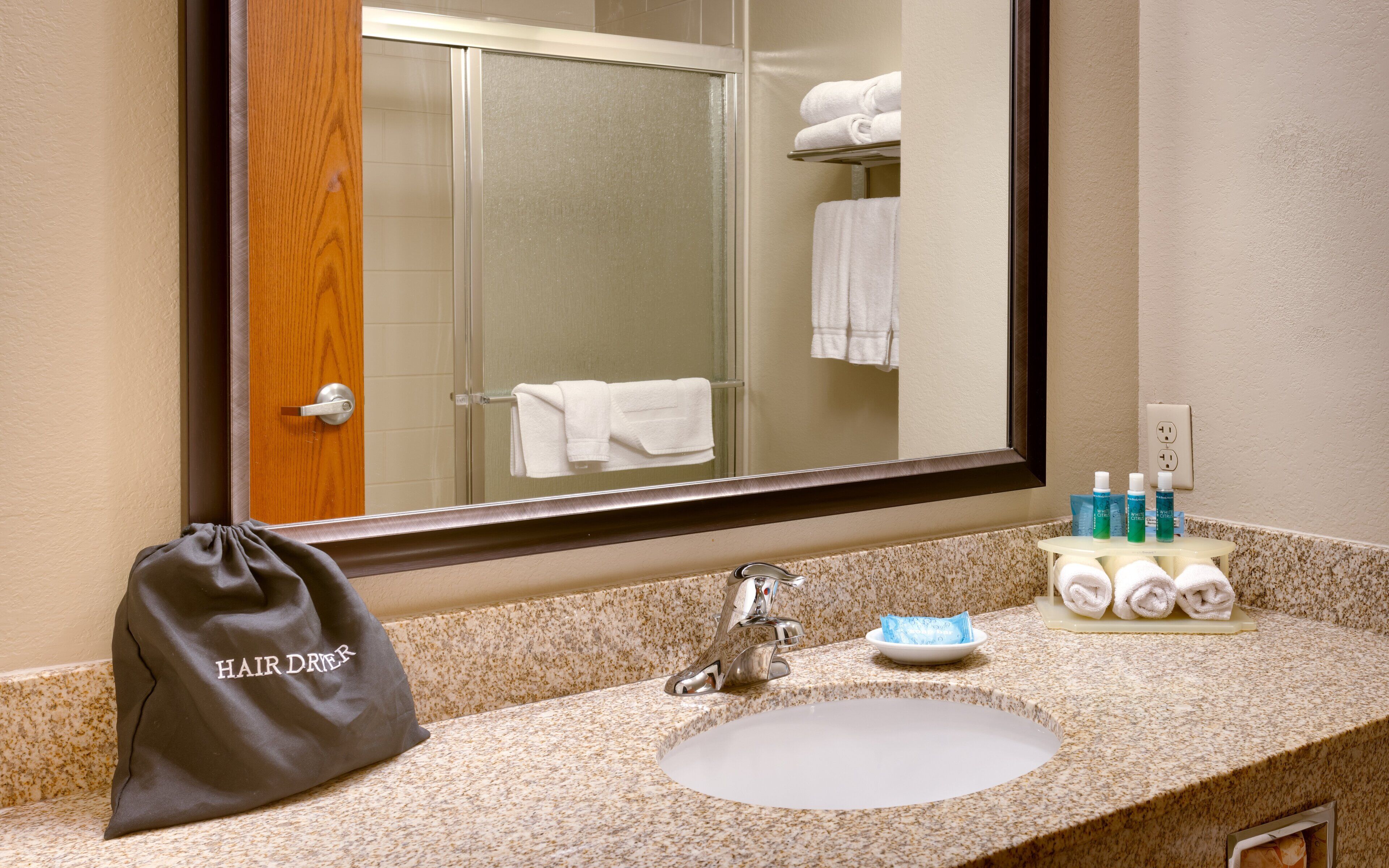 A bathroom with a sink, mirror, and toiletries.