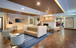 A hotel lobby with a seating area, a flat-screen TV, a fireplace, and a dining area. - Holiday Inn Express & Suites Orem-North Provo by IHG (Orem)