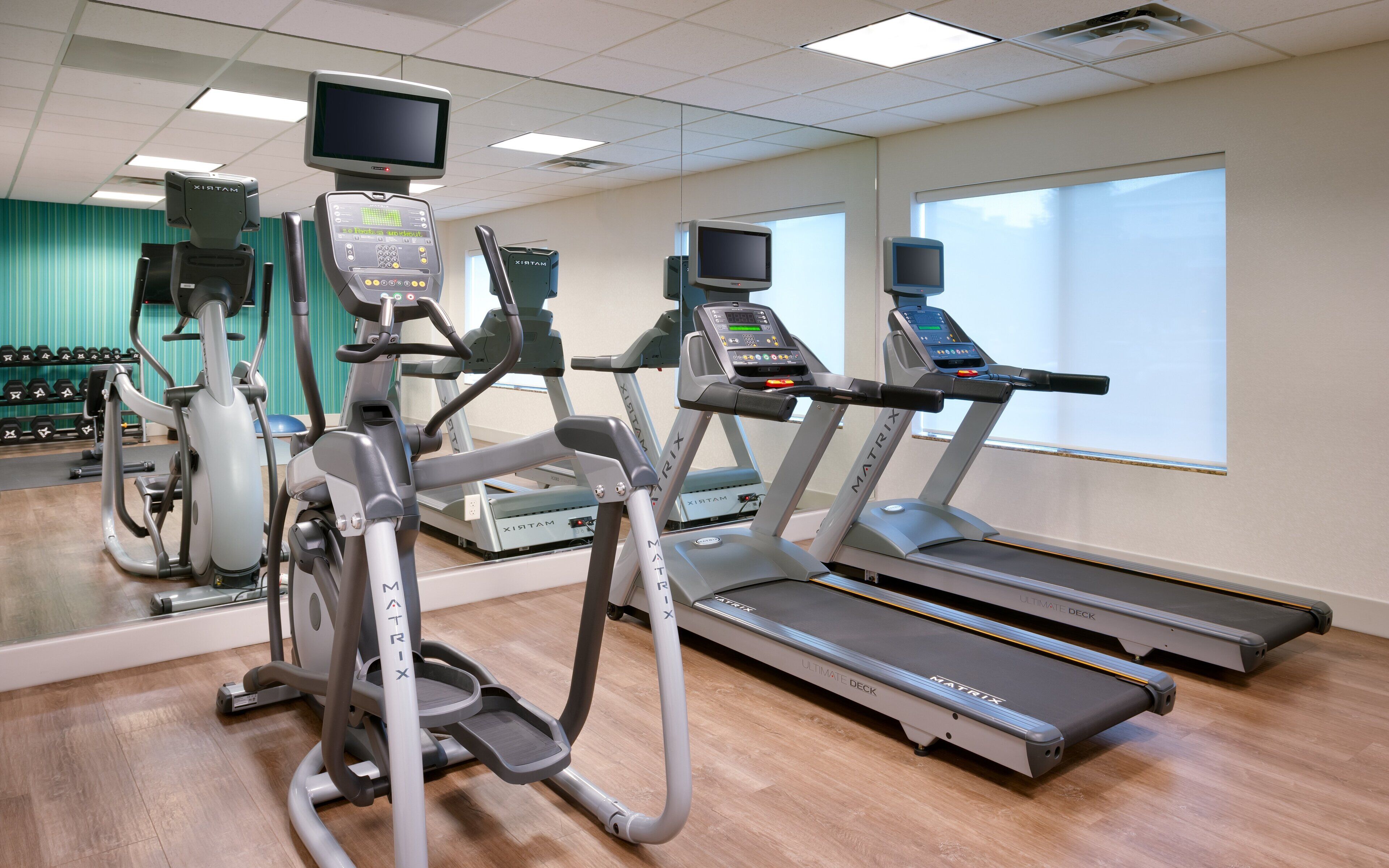 A gym with treadmills, an elliptical, and a stationary bike, all with digital displays.