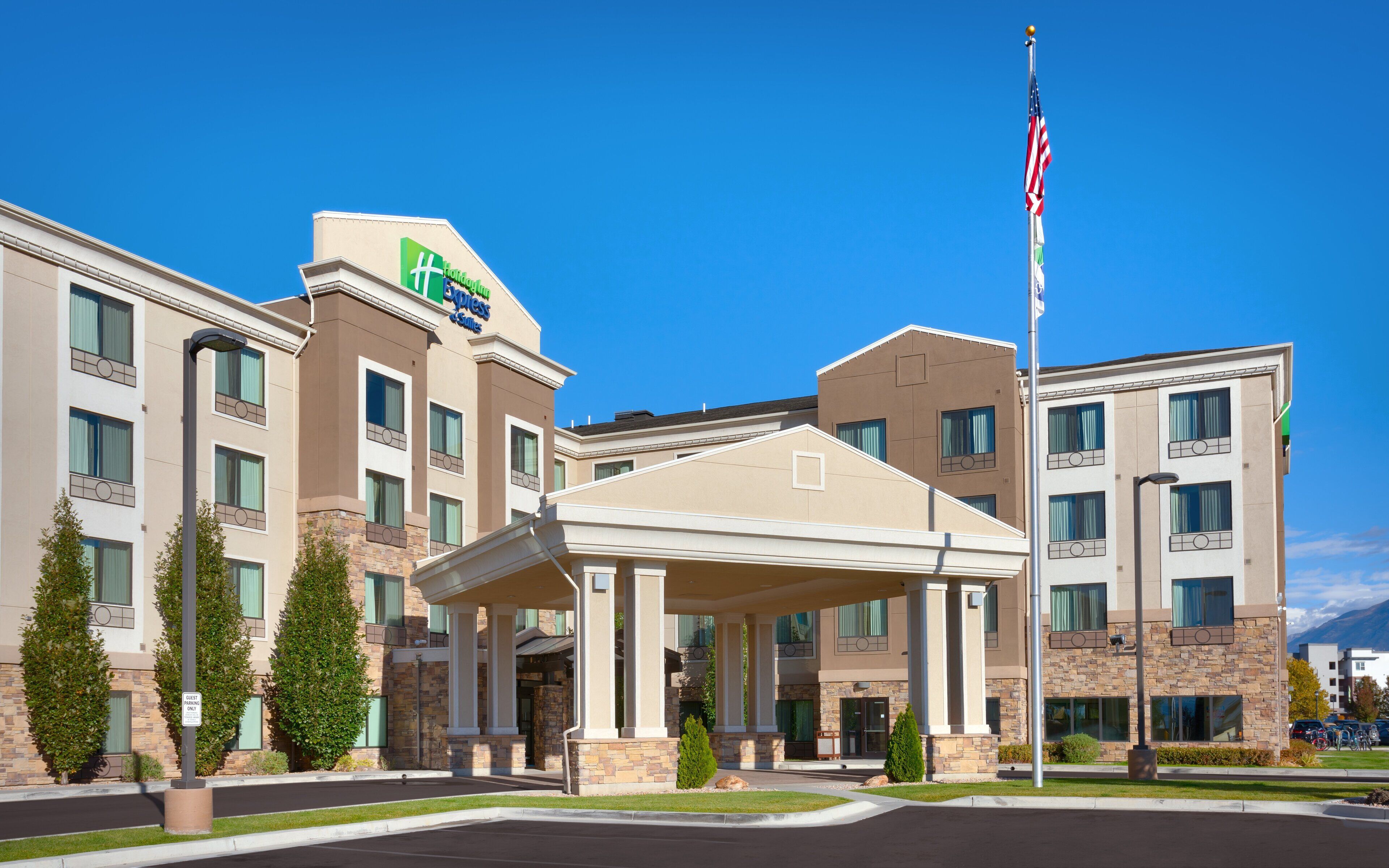 A hotel with a covered entrance, multiple floors, and a flagpole with the American flag.