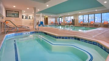 A swimming pool with a tiled edge, a ladder, and seating areas with chairs.