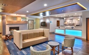 A hotel lobby with a reception desk, a fireplace, a sofa, and a small table. - Holiday Inn Express & Suites Orem-North Provo by IHG (Orem)