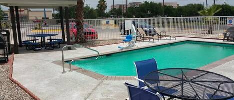 A swimming pool with lounge chairs and a covered seating area.