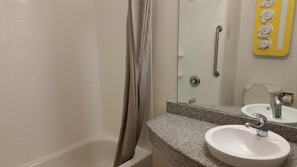 A bathroom with a bathtub, a sink with a mirror, and a shower curtain.