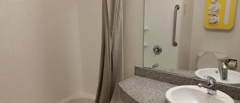 A bathroom with a bathtub, a sink with a mirror, and a shower curtain.