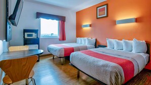 Habitación de hotel con dos camas, un escritorio, televisor, microondas y ventana con cortinas.