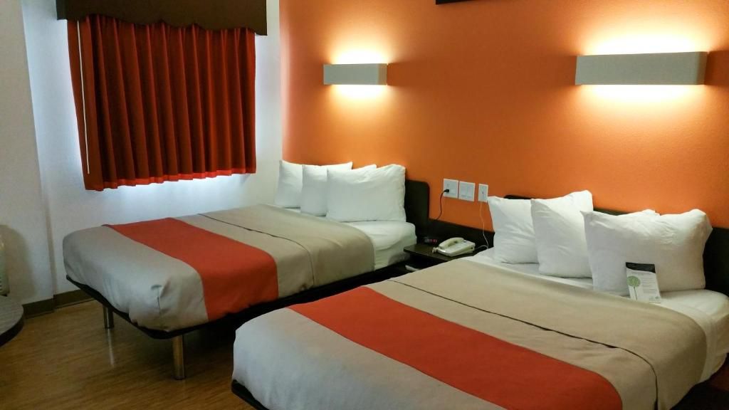 Ein Hotelzimmer mit zwei Betten, einem Nachttisch und einem roten Vorhang.