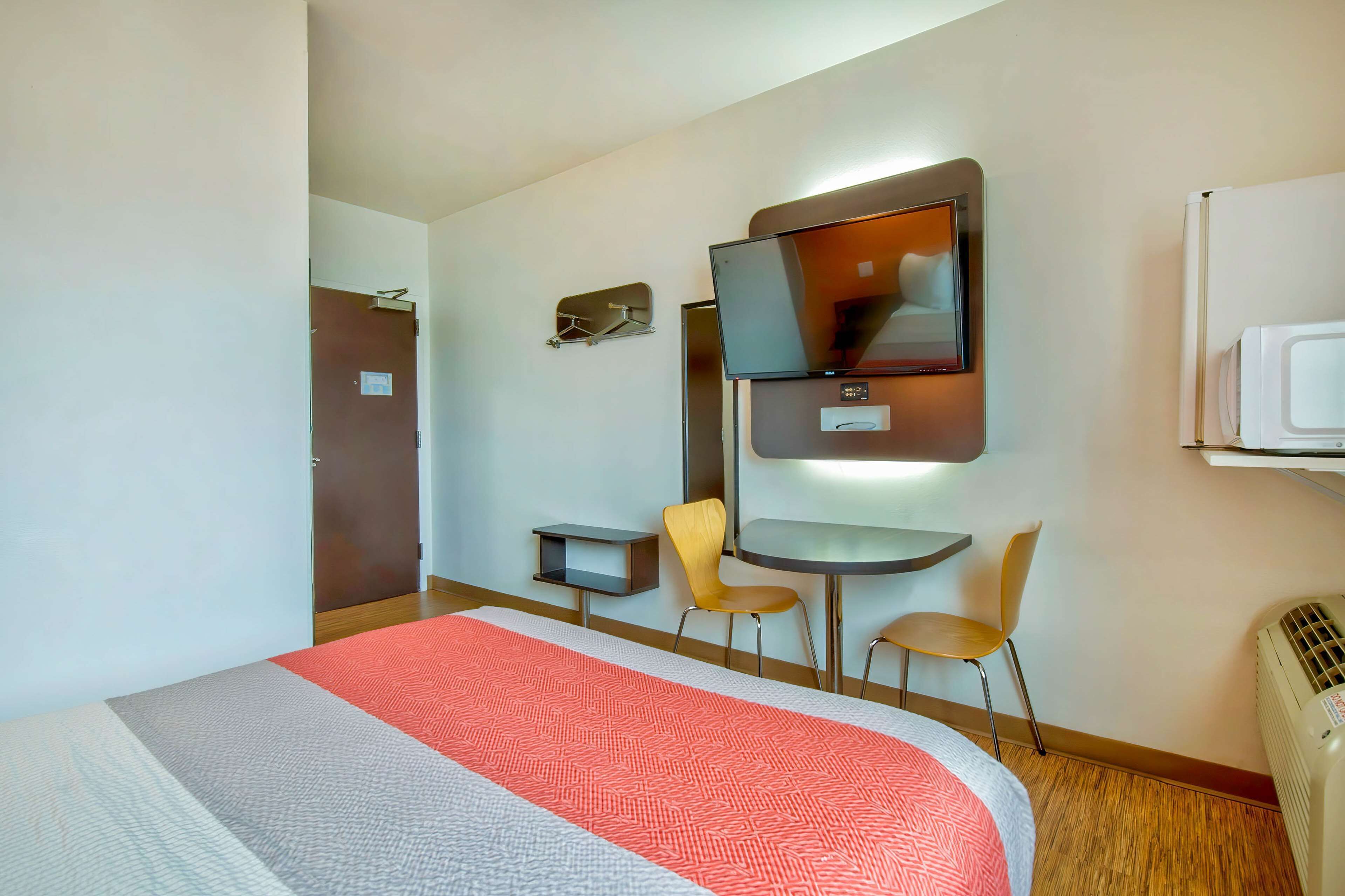 Een hotelkamer met een bed, een bureau, een stoel, een televisie en een verwarming.