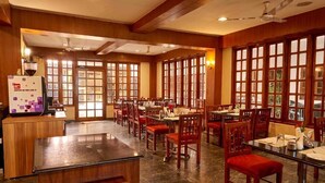 Een ruim restaurant met houten lambrisering, grote ramen en meerdere eettafels.
