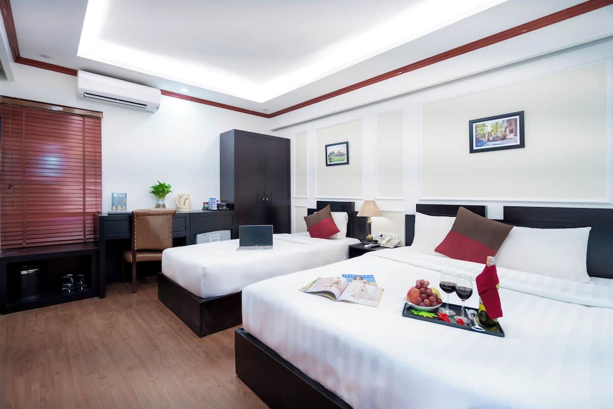 Een hotelkamer met twee bedden, een bureau, een kledingkast en een televisie.