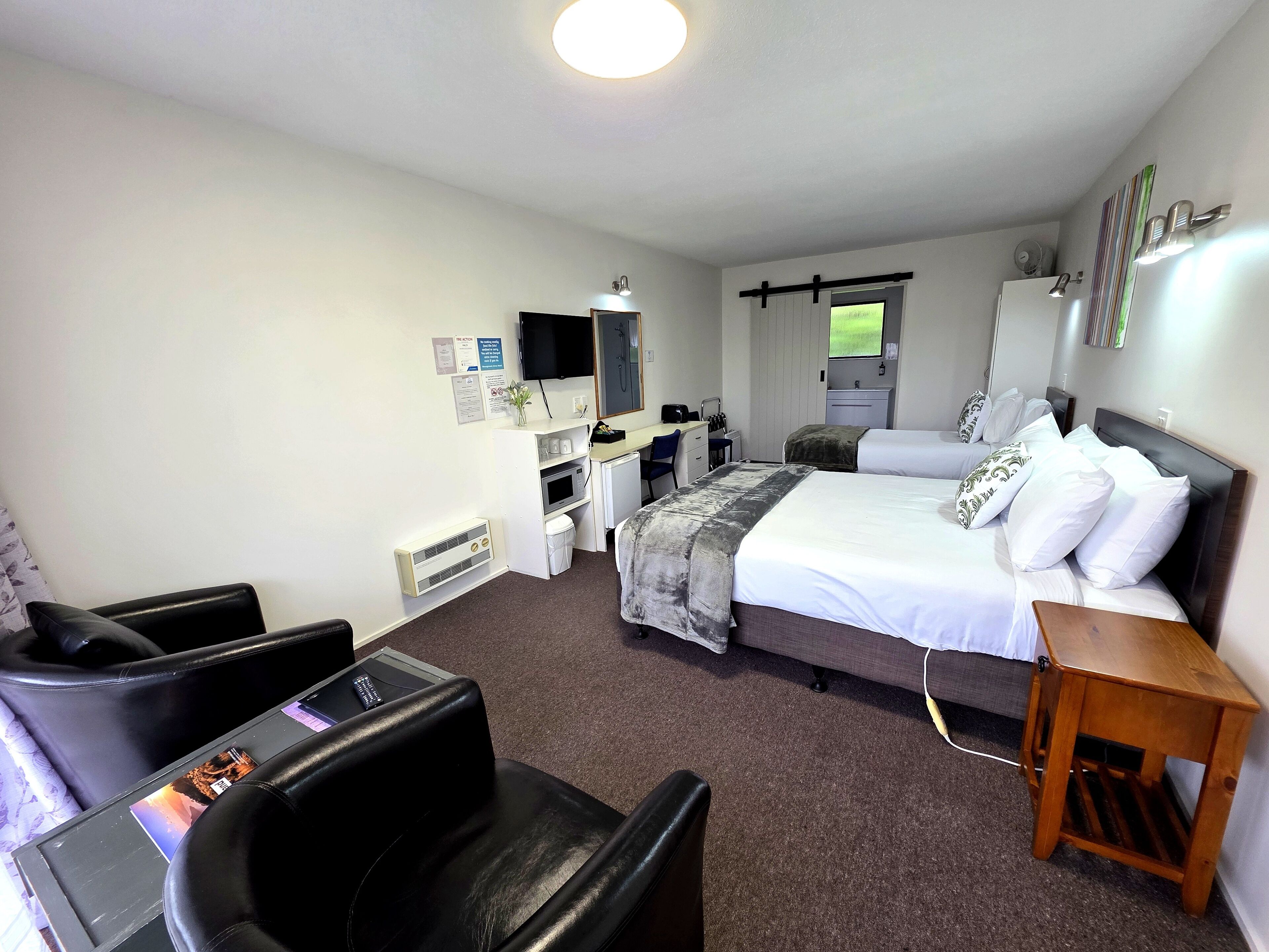 A hotel room with a bed, a desk, a chair, a television, and a bathroom.