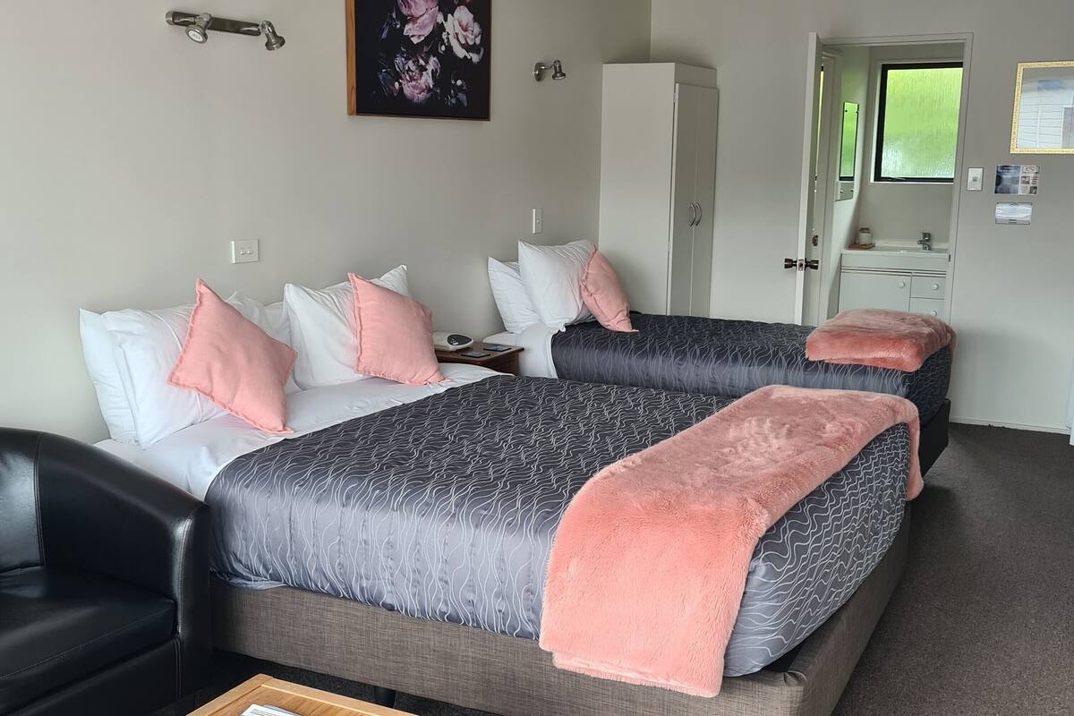 A hotel room with two beds, a wardrobe, a desk, and a mirror.