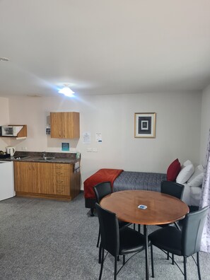 Un espacio habitable compacto con kitchenette, zona de comedor y sofá.