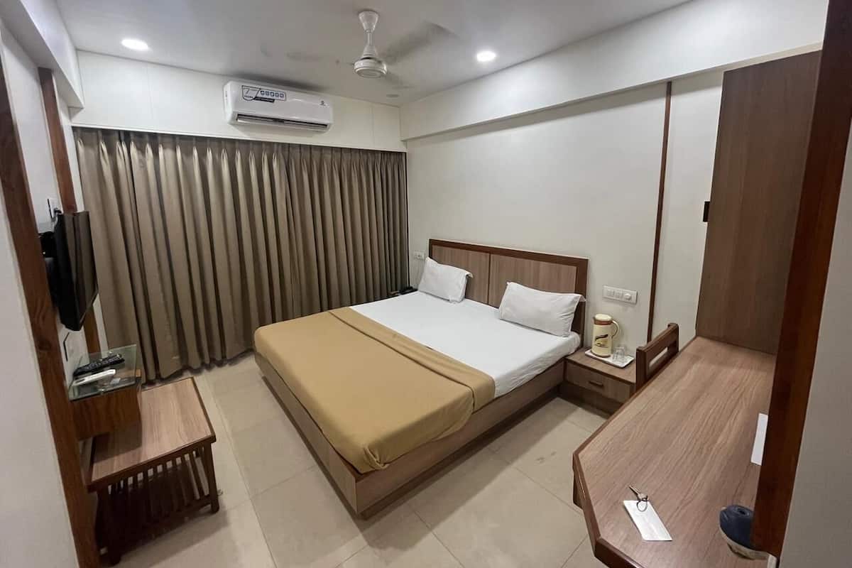 Habitación de hotel con cama, mesita de noche, televisor y aire acondicionado.