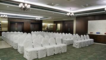 A conference room with rows of white-covered chairs, a whiteboard, and a reception desk.