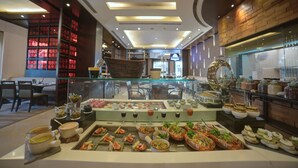 A buffet area with various food stations and a seating area with tables and chairs. - Goldfinch Hotel Delhi NCR (Faridabad)