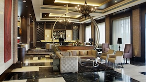 A modern lobby with a bar area, seating, and a chandelier. - Goldfinch Hotel Delhi NCR (Faridabad)
