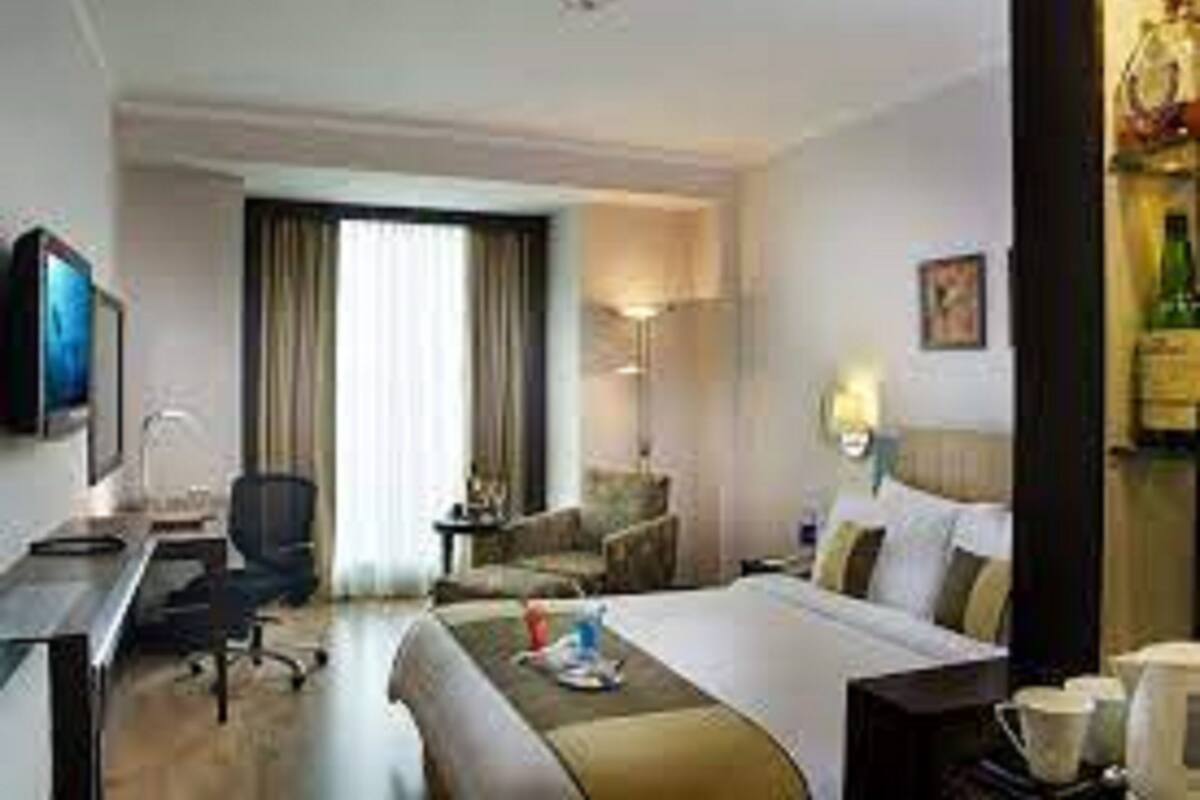 Ein Hotelzimmer mit einem Bett, einem Schreibtisch, einem Sessel, einer Lampe und einem Fernseher.