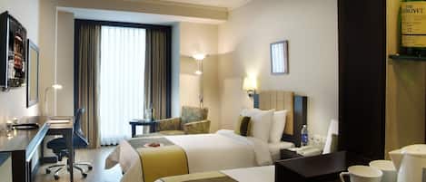Una habitación de hotel con dos camas, un escritorio, una silla, una lámpara, un televisor y una cafetera.