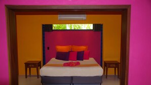 A bedroom with a bed, two nightstands, a window, and a red rug. - Pink Flamingo Resort (Port Douglas)