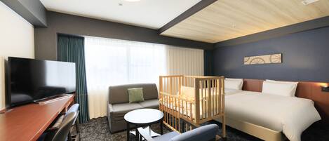 Una habitación de hotel con una cama, un escritorio, un televisor, un sofá y una cuna.