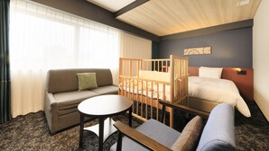 A hotel room with a bed, a sofa, a small table, and a crib.