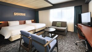 A hotel room with two beds, a sofa, a TV, and a small table.
