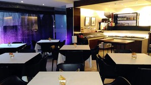 Un restaurant avec des tables et des chaises, un bar avec des bouteilles et un piano.