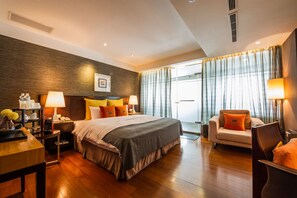 A hotel room with a large bed, bedside tables, a desk, a chair, and a view of the outdoors through curtains.
