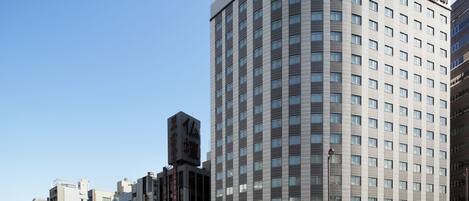 A modern hotel with a curved facade, multiple floors, and a prominent entrance.