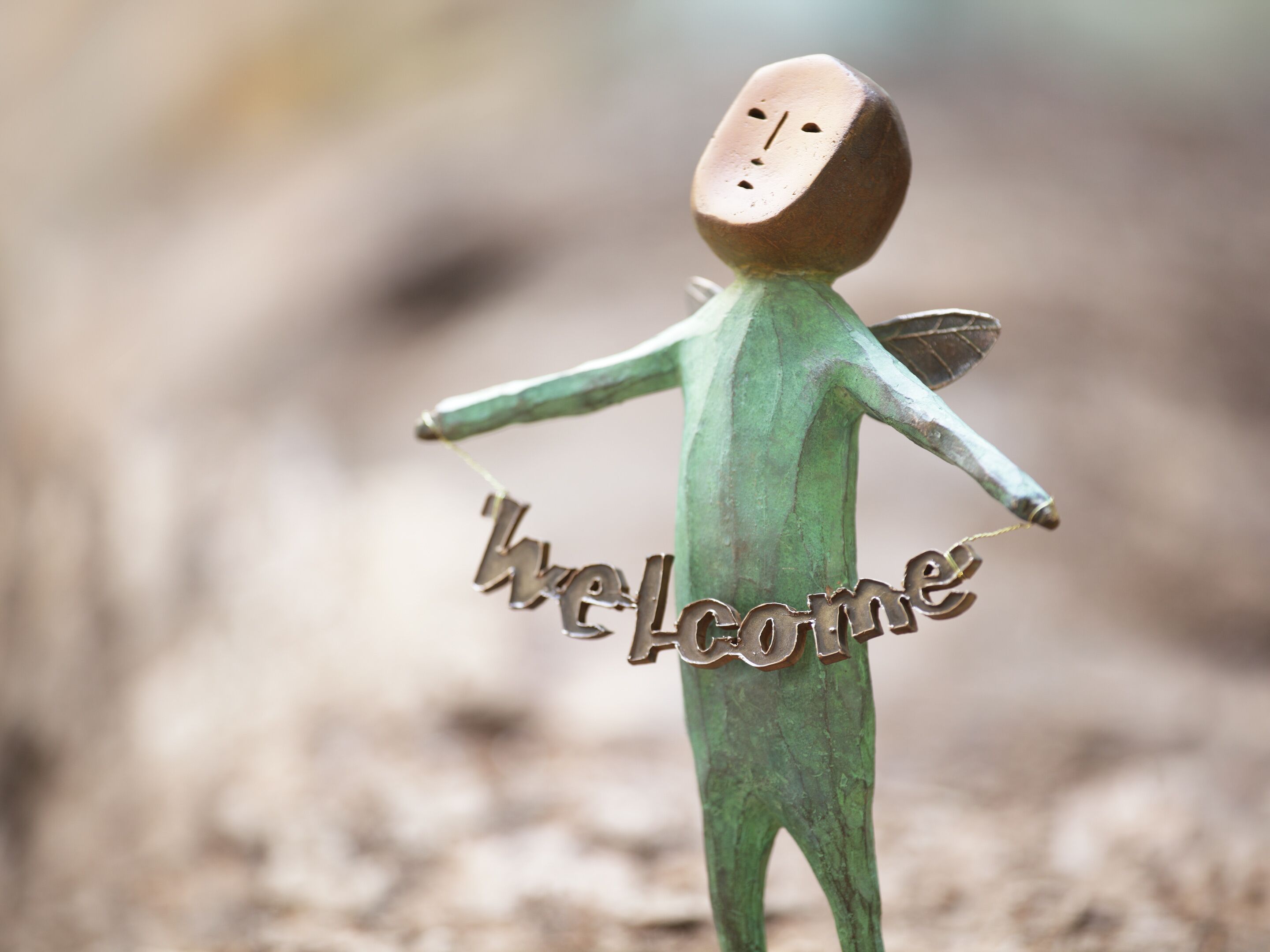 A wooden figure with outstretched arms and the word "Welcome" on its torso.