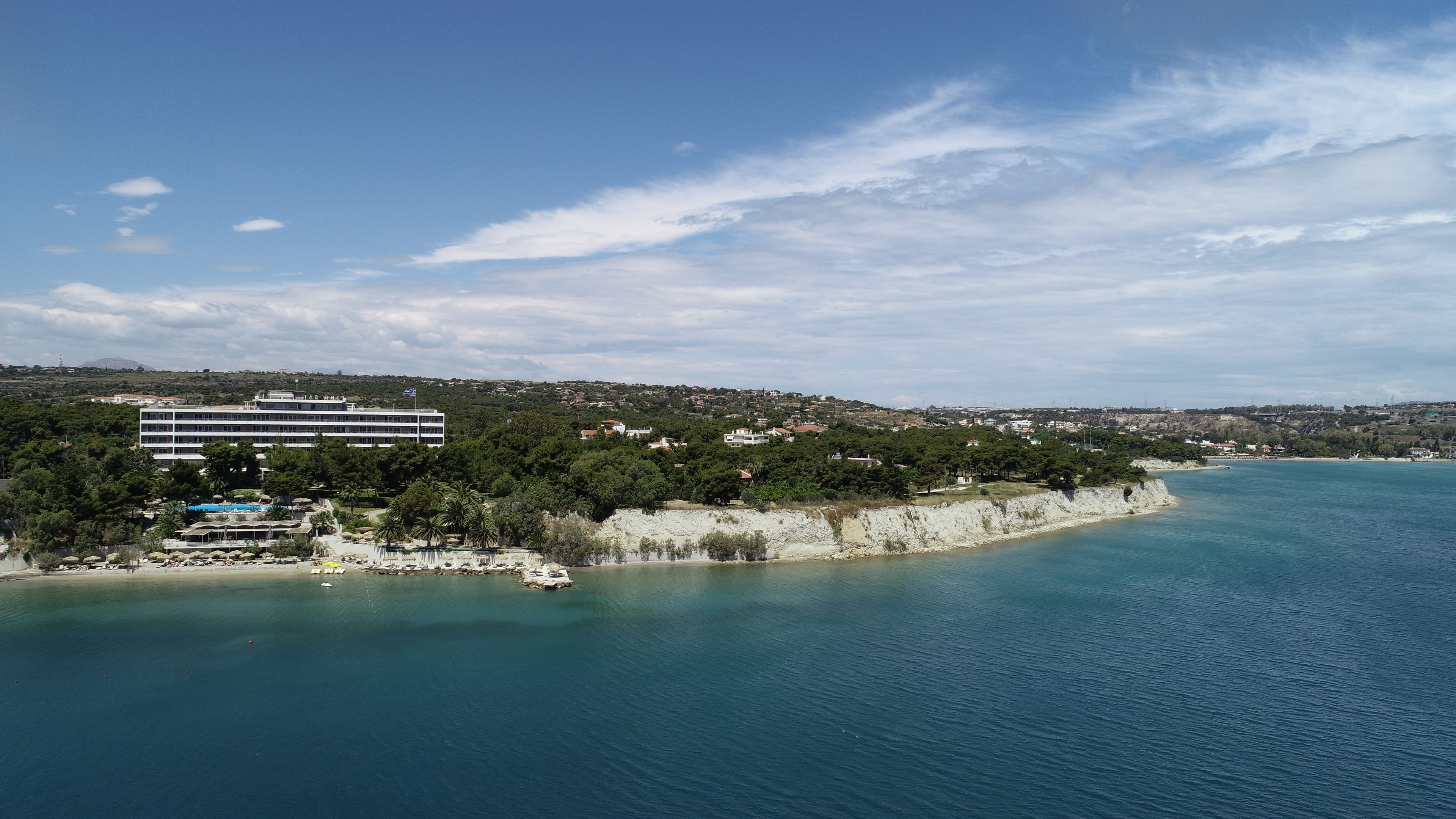 A coastal area with a large building, a beach, and a clear view of the sea.