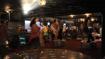 Un espacio interior lleno de gente, con una bola de discoteca, mesas y sillas.