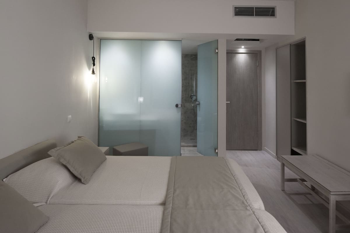 Un dormitorio moderno con cama, mesita de noche y televisor montado en la pared.